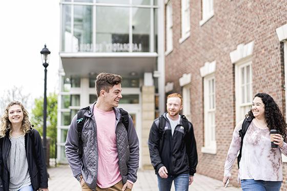 四名波胆网站学生下课后离开教学楼的照片, 边走边聊. 