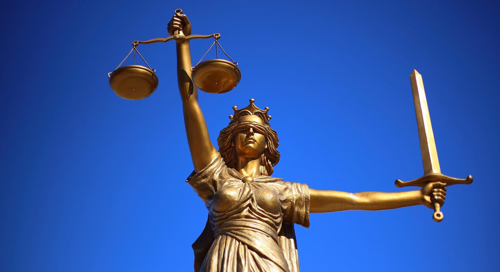 一张金色的正义雕像的照片，一个蒙着眼睛的女人拿着剑和法律秤. 